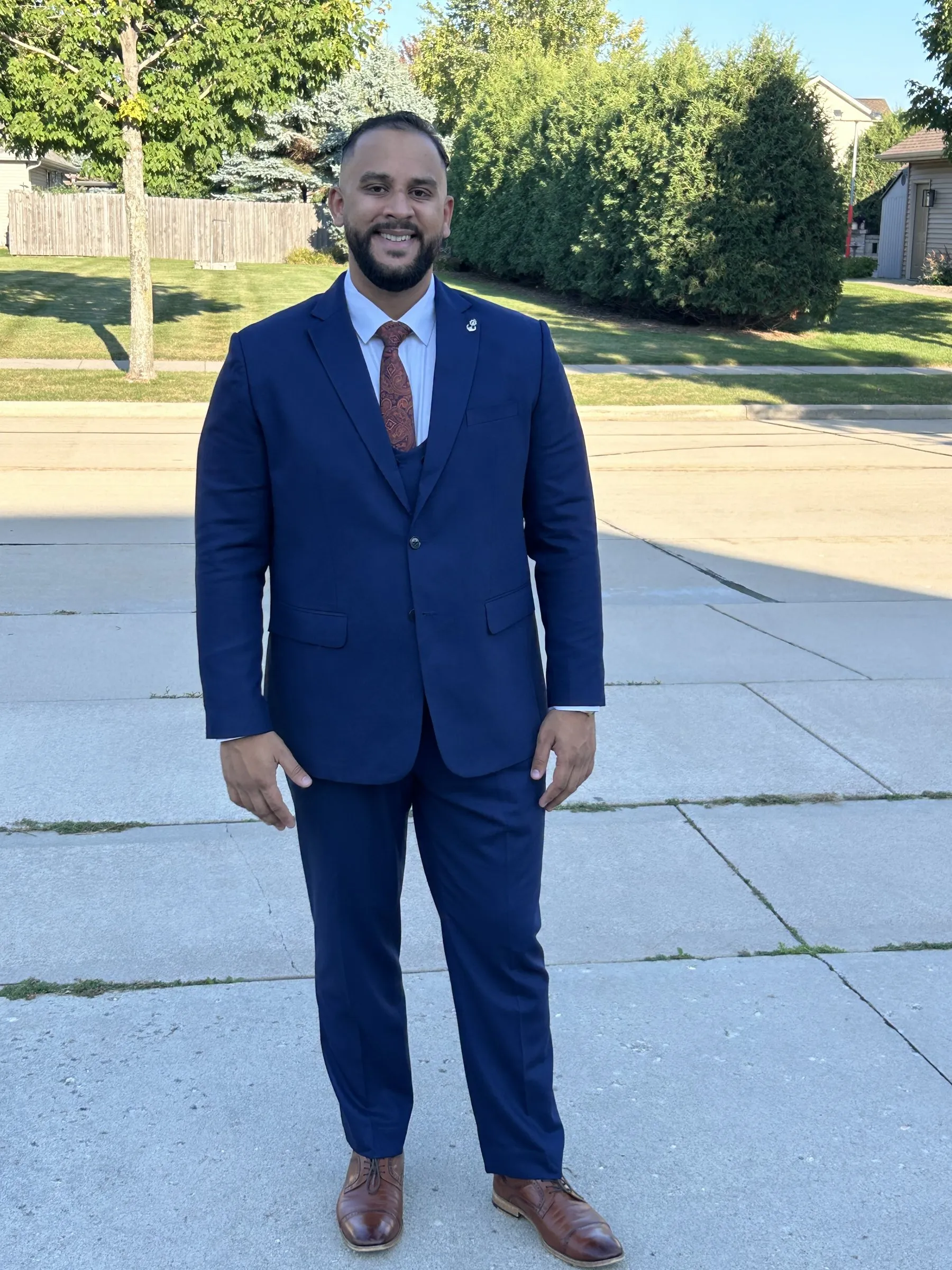 Addy in a navy three-piece suit, smiling at the camera